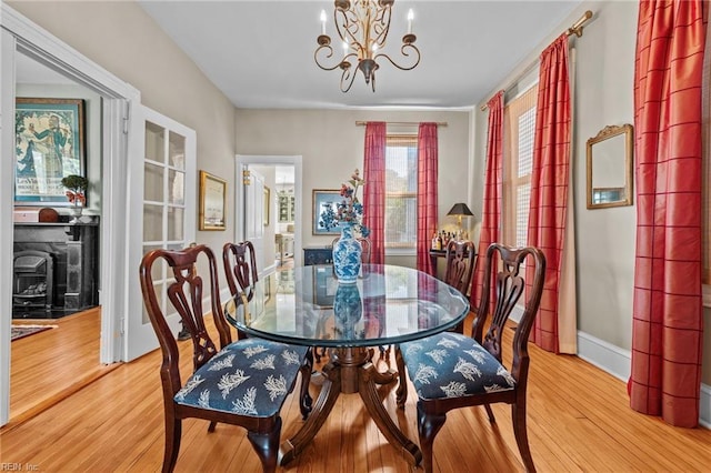 dining room with a wood stove, light hardwood / wood-style flooring, and an inviting chandelier