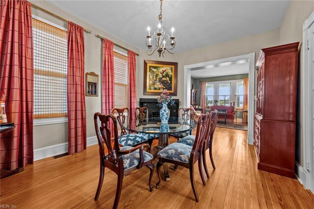 dining space featuring light wood-type flooring and an inviting chandelier