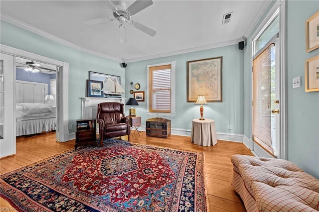 sitting room featuring ceiling fan, wood-type flooring, and ornamental molding