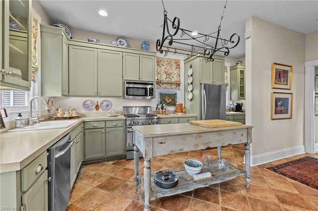 kitchen with green cabinets, sink, light tile patterned floors, appliances with stainless steel finishes, and a chandelier