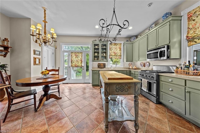 kitchen featuring stainless steel appliances, pendant lighting, an inviting chandelier, tile patterned flooring, and green cabinets