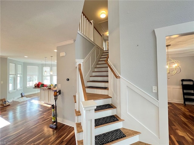 stairs featuring an inviting chandelier, wood-type flooring, and ornamental molding