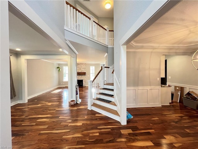 stairway featuring a fireplace, wood-type flooring, and crown molding