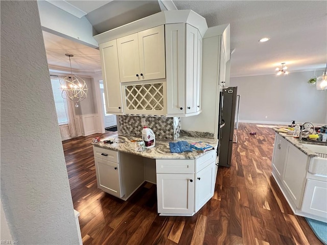 kitchen featuring white cabinets, light stone countertops, ornamental molding, and hanging light fixtures