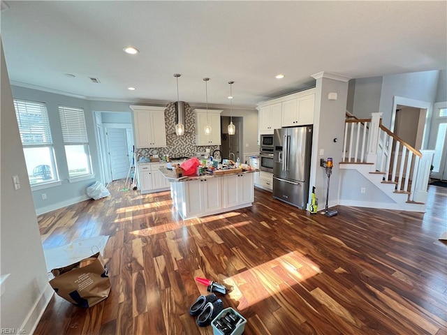 kitchen with white cabinets, hanging light fixtures, wall chimney range hood, and appliances with stainless steel finishes