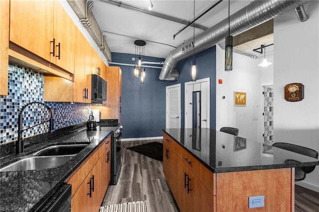 kitchen featuring dark wood-type flooring, dark stone counters, black appliances, sink, and hanging light fixtures