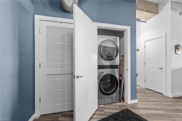 clothes washing area featuring light hardwood / wood-style floors and stacked washer / dryer