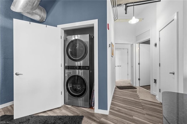 clothes washing area featuring hardwood / wood-style floors and stacked washer and clothes dryer