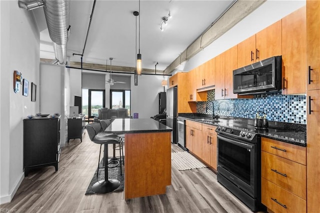 kitchen featuring ceiling fan, a center island, hanging light fixtures, stainless steel appliances, and a kitchen breakfast bar