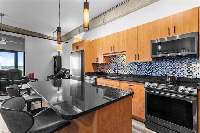 kitchen featuring a breakfast bar, stainless steel appliances, a kitchen island, and hanging light fixtures