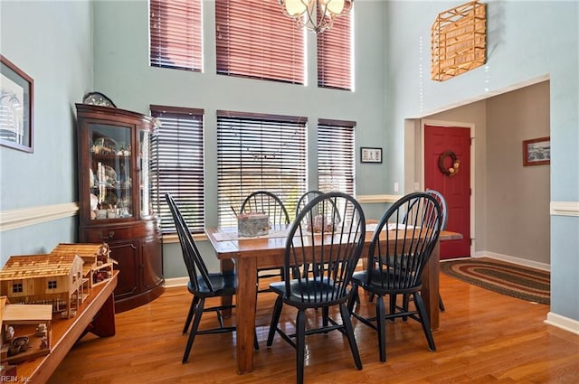 dining space with a notable chandelier, a high ceiling, and hardwood / wood-style flooring