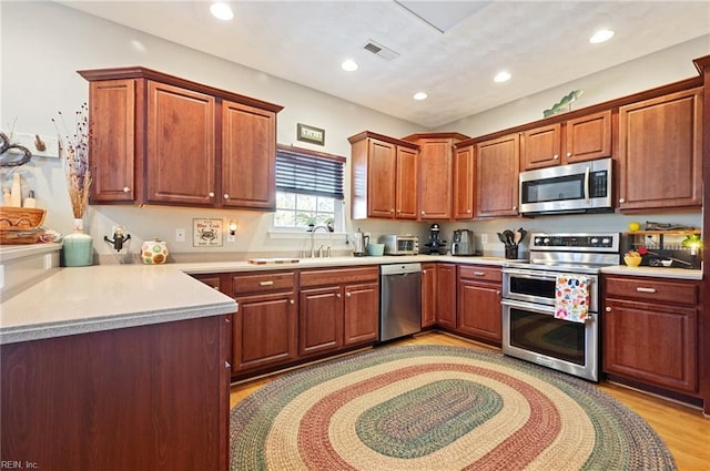 kitchen featuring sink, light wood-type flooring, and appliances with stainless steel finishes