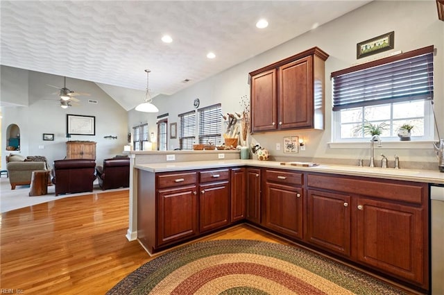 kitchen with kitchen peninsula, sink, pendant lighting, and lofted ceiling