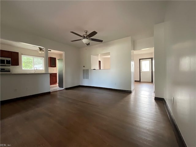 unfurnished living room featuring dark hardwood / wood-style flooring, ceiling fan, and plenty of natural light