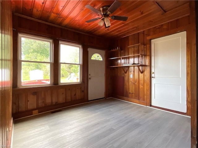 empty room featuring wooden walls, ceiling fan, wooden ceiling, and light hardwood / wood-style floors