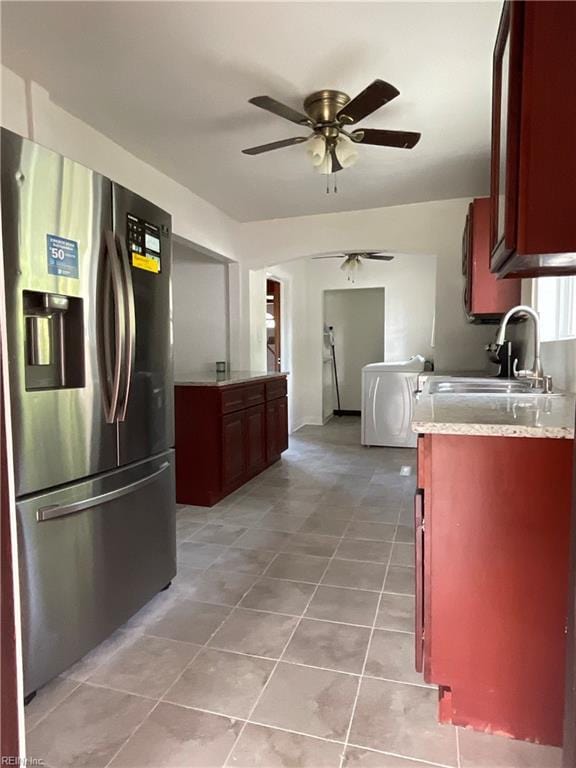 kitchen with ceiling fan, sink, stainless steel fridge with ice dispenser, washer / dryer, and light tile patterned flooring