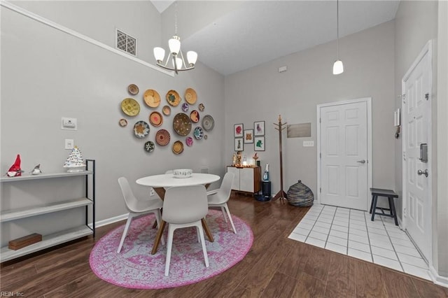 dining area with high vaulted ceiling, wood-type flooring, and an inviting chandelier