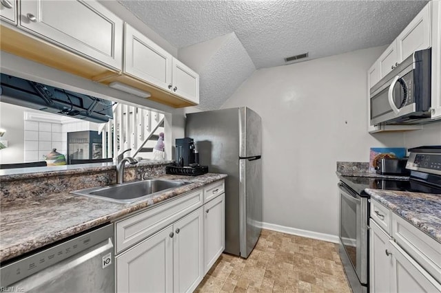 kitchen with white cabinets, appliances with stainless steel finishes, a textured ceiling, and sink