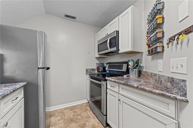 kitchen with white cabinets, stainless steel appliances, stone counters, and lofted ceiling