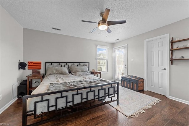 bedroom with ceiling fan, dark hardwood / wood-style flooring, and a textured ceiling