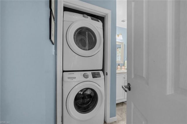 washroom with stacked washer / dryer and light tile patterned flooring