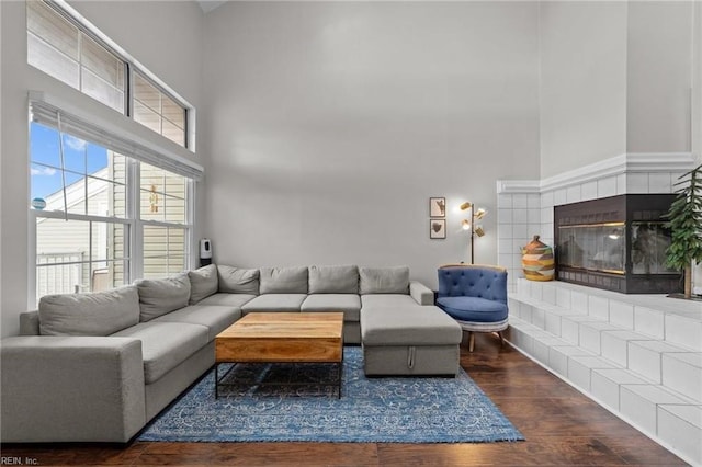 living room featuring a tile fireplace and dark wood-type flooring