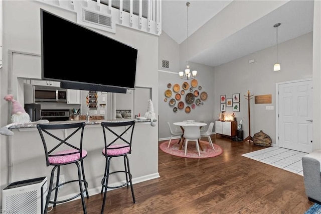 kitchen featuring white cabinets, hardwood / wood-style flooring, hanging light fixtures, and high vaulted ceiling