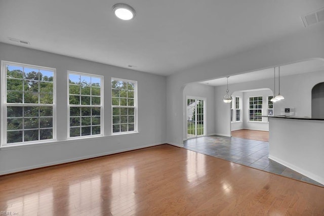 unfurnished living room featuring a chandelier and hardwood / wood-style floors