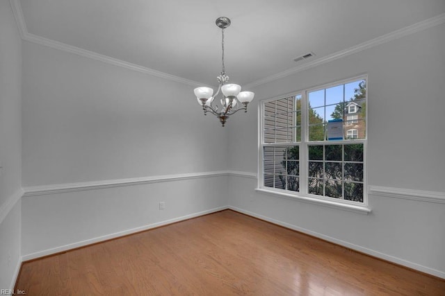 spare room featuring hardwood / wood-style flooring, crown molding, and an inviting chandelier