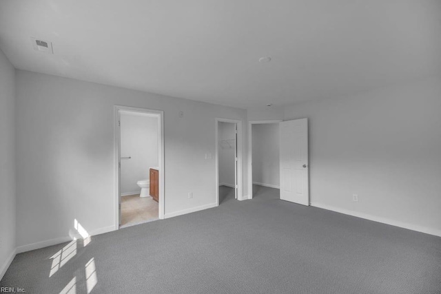 unfurnished bedroom with light colored carpet, connected bathroom, and a closet