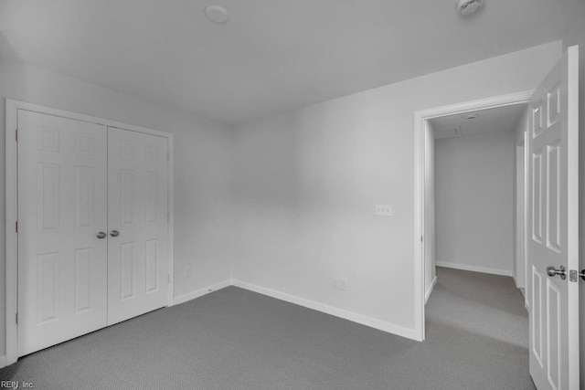 unfurnished bedroom with dark carpet and a closet