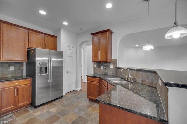 kitchen with pendant lighting, decorative backsplash, stainless steel fridge with ice dispenser, and sink