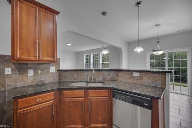 kitchen with dishwasher, dark stone counters, sink, hanging light fixtures, and tile patterned flooring