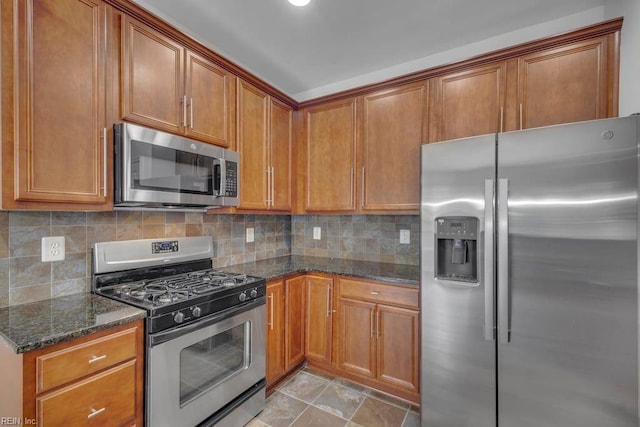 kitchen with light tile patterned floors, stainless steel appliances, dark stone counters, and tasteful backsplash