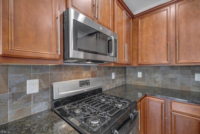 kitchen featuring gas stove, backsplash, and dark stone countertops