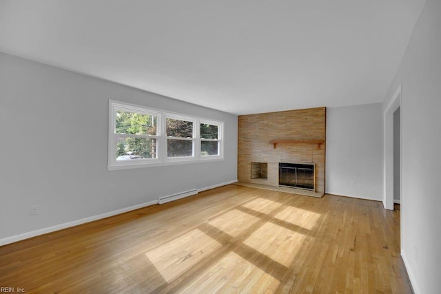 unfurnished living room featuring light wood-type flooring and a brick fireplace