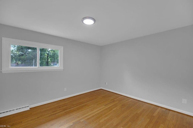 unfurnished room with wood-type flooring and baseboard heating