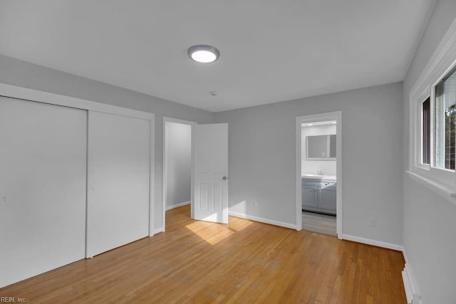 unfurnished bedroom with ensuite bathroom, a closet, light hardwood / wood-style floors, and sink