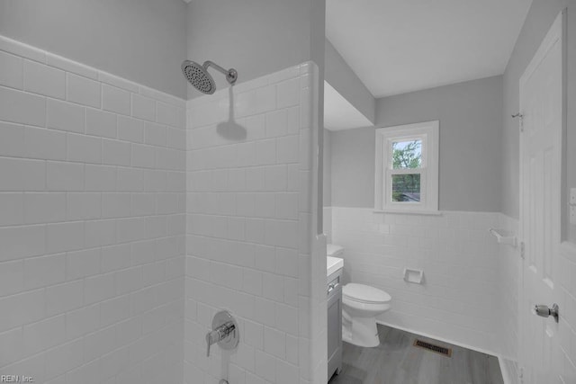 full bathroom featuring bathtub / shower combination, vanity, wood-type flooring, tile walls, and toilet