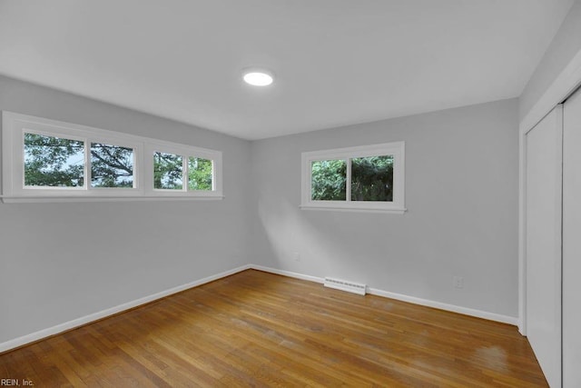 unfurnished bedroom with a closet, light wood-type flooring, and multiple windows