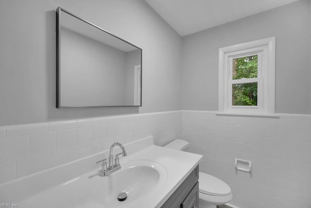 bathroom featuring vanity, toilet, and tile walls