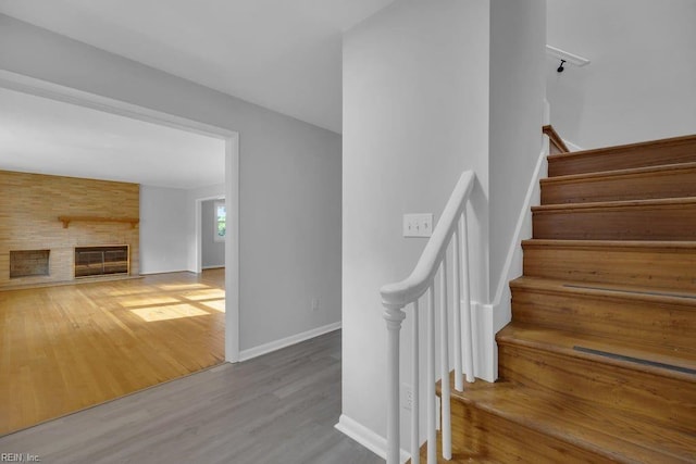 stairway featuring wood-type flooring and a large fireplace