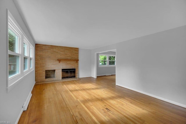 unfurnished living room with a large fireplace, hardwood / wood-style floors, and a baseboard radiator