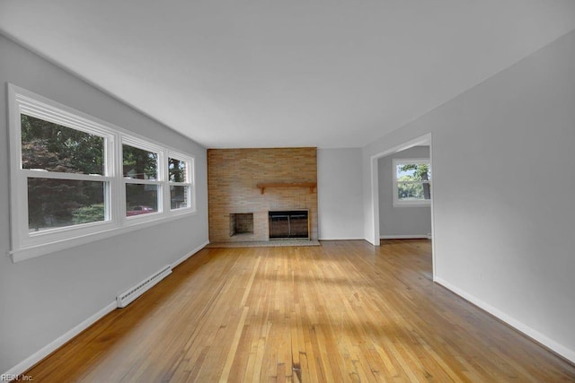 unfurnished living room with a fireplace, light hardwood / wood-style flooring, and a baseboard heating unit