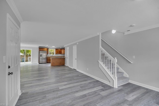 unfurnished living room with light wood-type flooring and crown molding