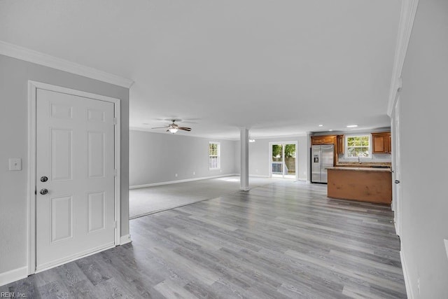 unfurnished living room with decorative columns, ceiling fan, crown molding, and light hardwood / wood-style floors