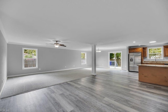 unfurnished living room with plenty of natural light, light hardwood / wood-style floors, and crown molding