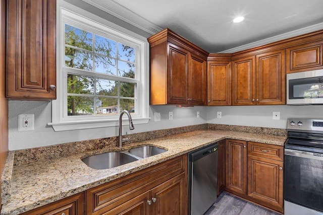 kitchen with light wood-type flooring, light stone counters, ornamental molding, stainless steel appliances, and sink