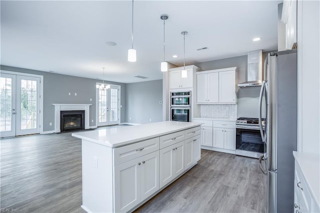 kitchen featuring french doors, stainless steel appliances, a kitchen island, and white cabinetry