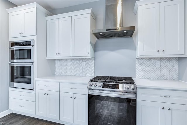 kitchen with backsplash, white cabinets, wall chimney exhaust hood, and stainless steel appliances